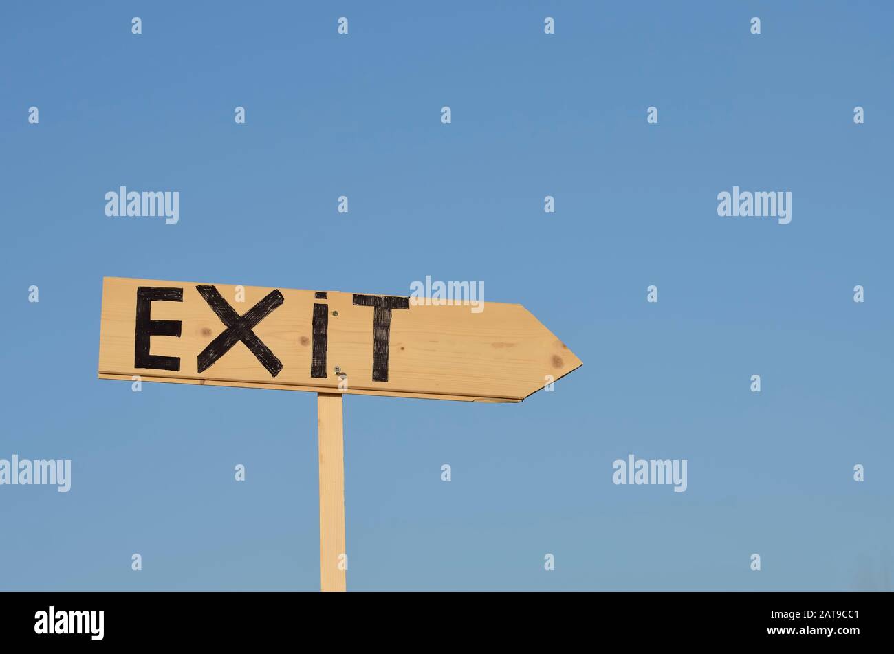 Segno di freccia in legno con la parola uscita. Sullo sfondo il cielo blu. Foto Stock