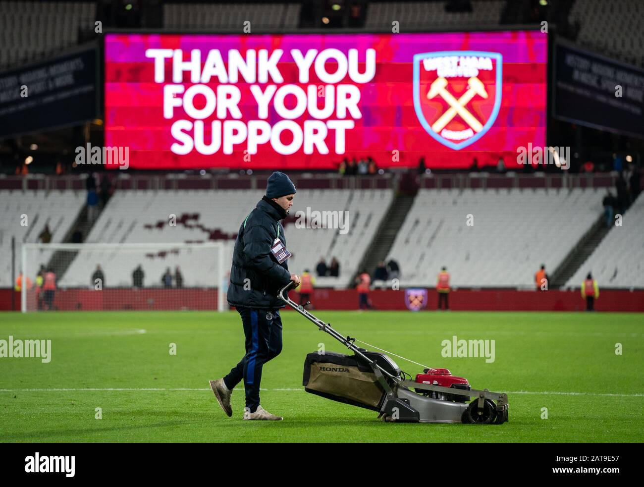 I groundsmen ottengono diritti a tagliare l'erba con i tosaerba dopo la partita durante la partita della Premier League tra il West Ham United e Liverpool al Foto Stock