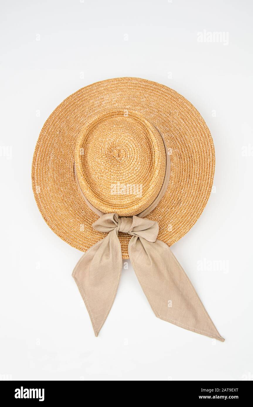 Cappello di paglia isolato su uno sfondo chiaro. Questo cappello da sole è ideale per lavorare in giardino e all'aperto, ha un nastro di tessuto beige legato. Foto Stock