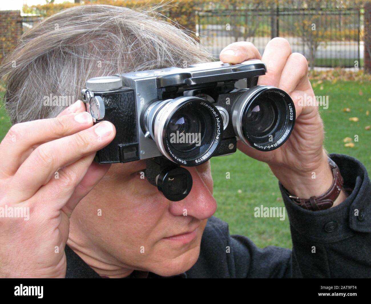 Fotografo che utilizza una fotocamera stereo 3D con obiettivi grandangolari collegati. Foto Stock