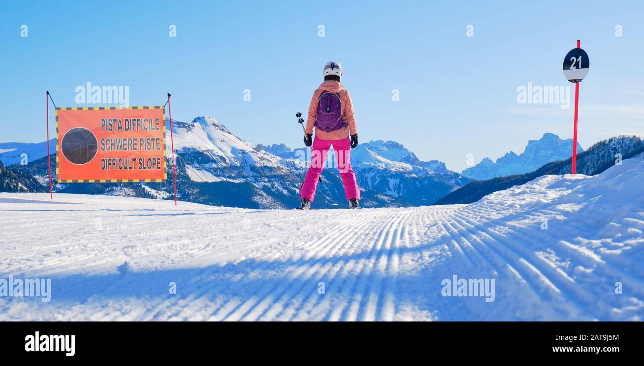 Sciatore femminile sul bordo di una pista da sci nera, guardando in  lontananza, accanto a un segno di pendenza che dice Difficile pendenza in  italiano, tedesco, e inglese, i Foto stock -