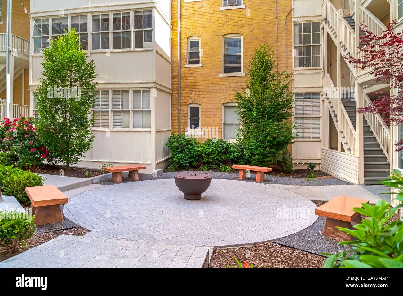 Panchine di pietra intorno ad un camino fuori di un edificio residenziale in una giornata di sole Foto Stock