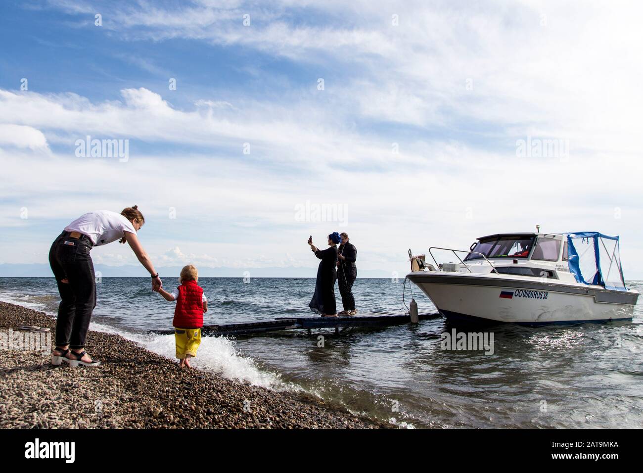 Turisti e barche sulla riva del lago Baikal a Listvyanka Foto Stock