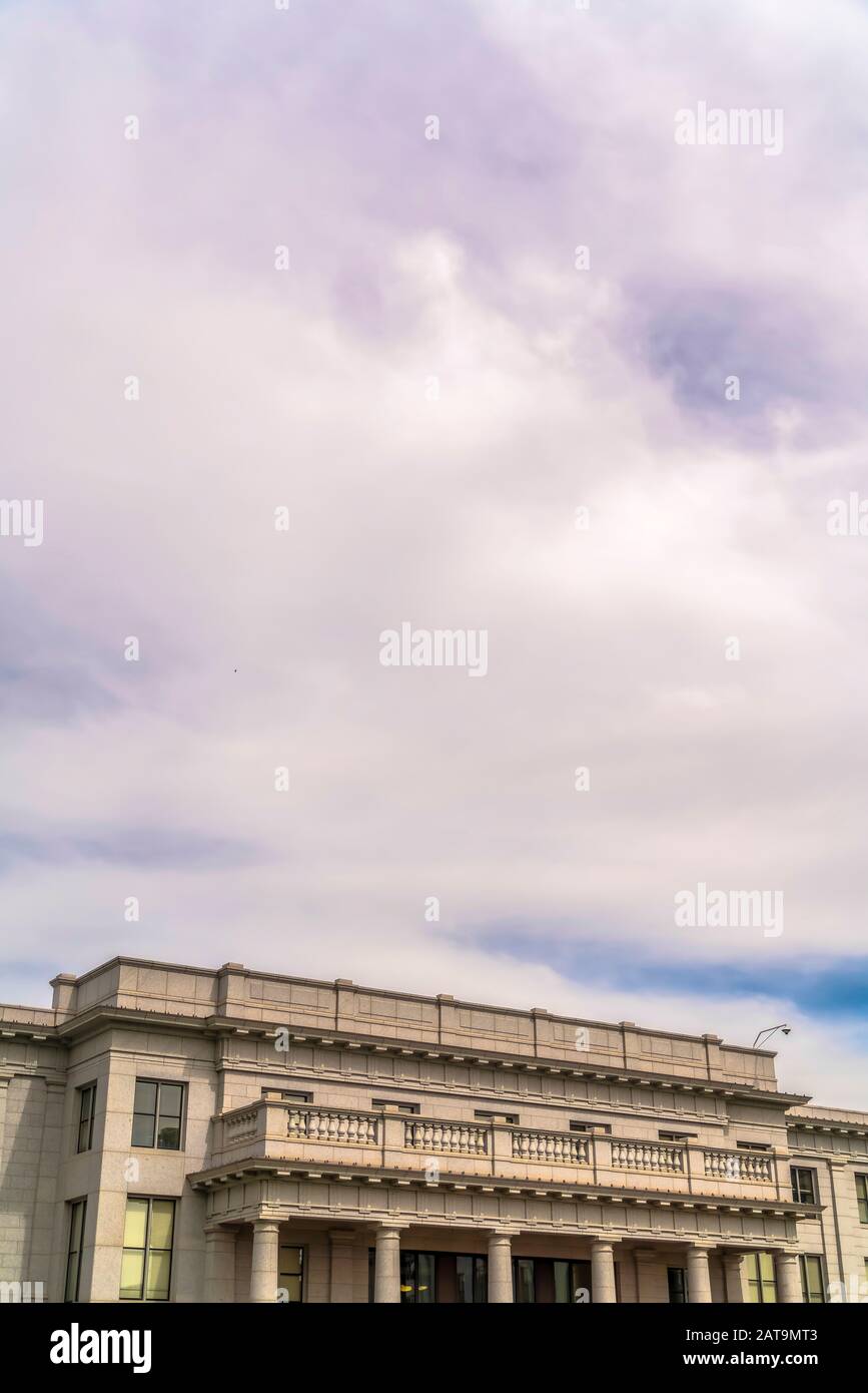 Cielo blu nuvoloso sopra l'edificio con balcone e colonne enormi all'entrata Foto Stock