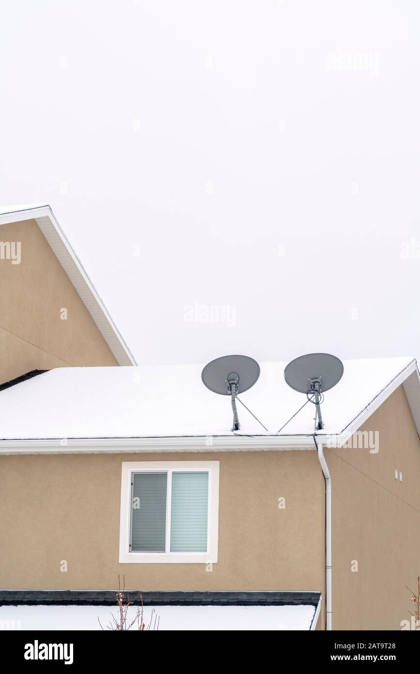 Piatti satellite sul tetto della casa coperta di neve in inverno Foto Stock