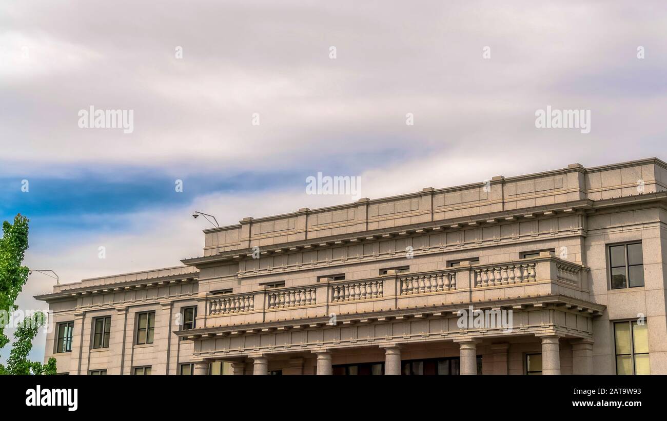 Edificio panoramico con balcone bianco e telecamera di sicurezza sul tetto contro il cielo nuvoloso Foto Stock
