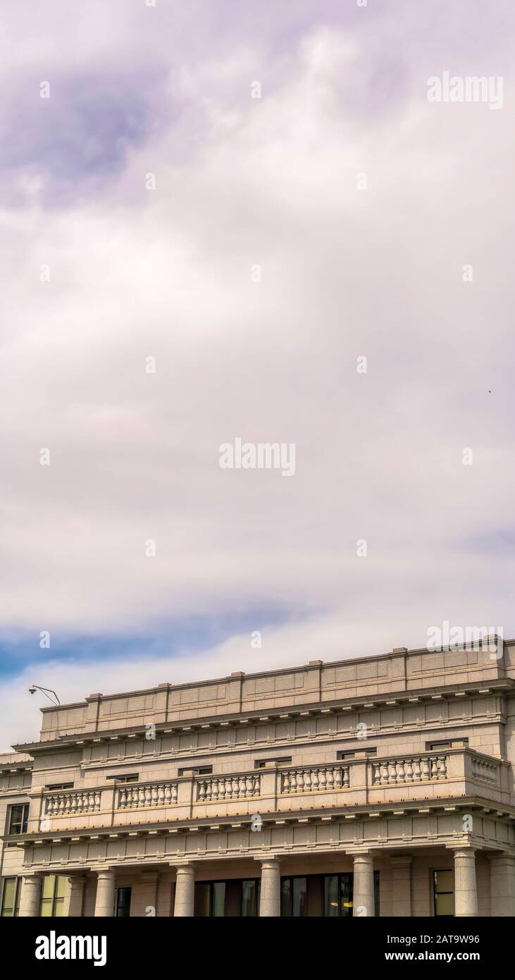 Telaio verticale cielo blu nuvoloso sopra l'edificio con balcone e colonne enormi all'ingresso Foto Stock