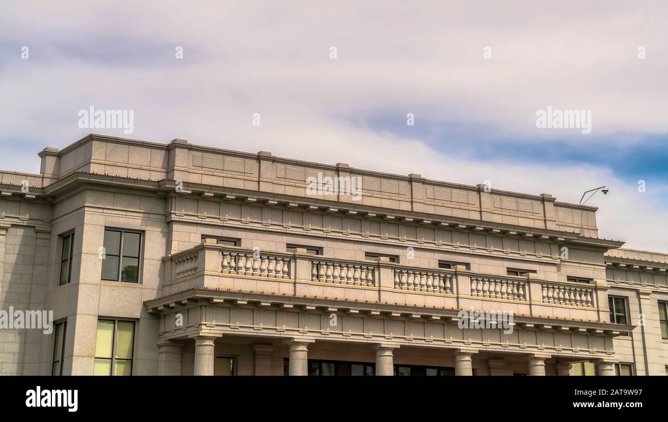 Panorama cielo blu nuvoloso sopra l'edificio con balcone e colonne enormi all'entrata Foto Stock