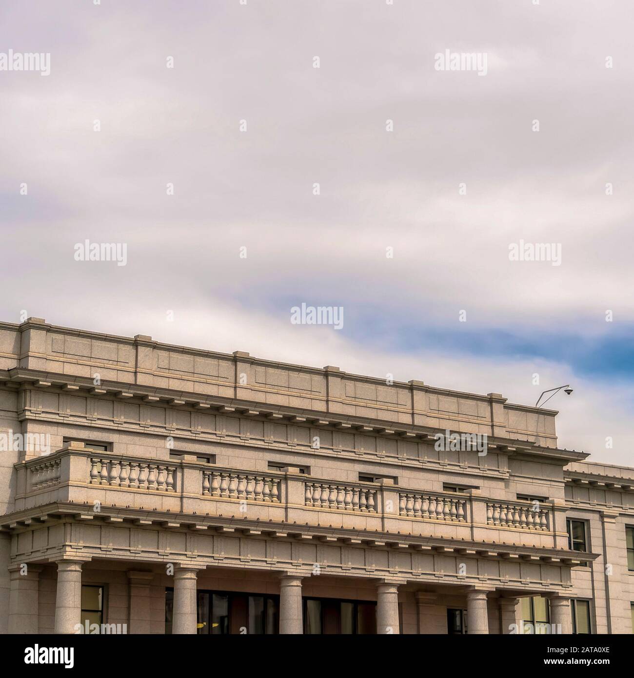 Edificio con cornice quadrata con balcone bianco e telecamera di sicurezza sul tetto contro il cielo nuvoloso Foto Stock