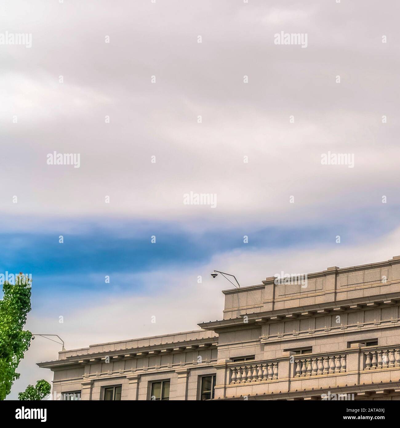 Edificio quadrato con balcone con parete bianca e telecamera di sicurezza sul tetto contro il cielo nuvoloso Foto Stock