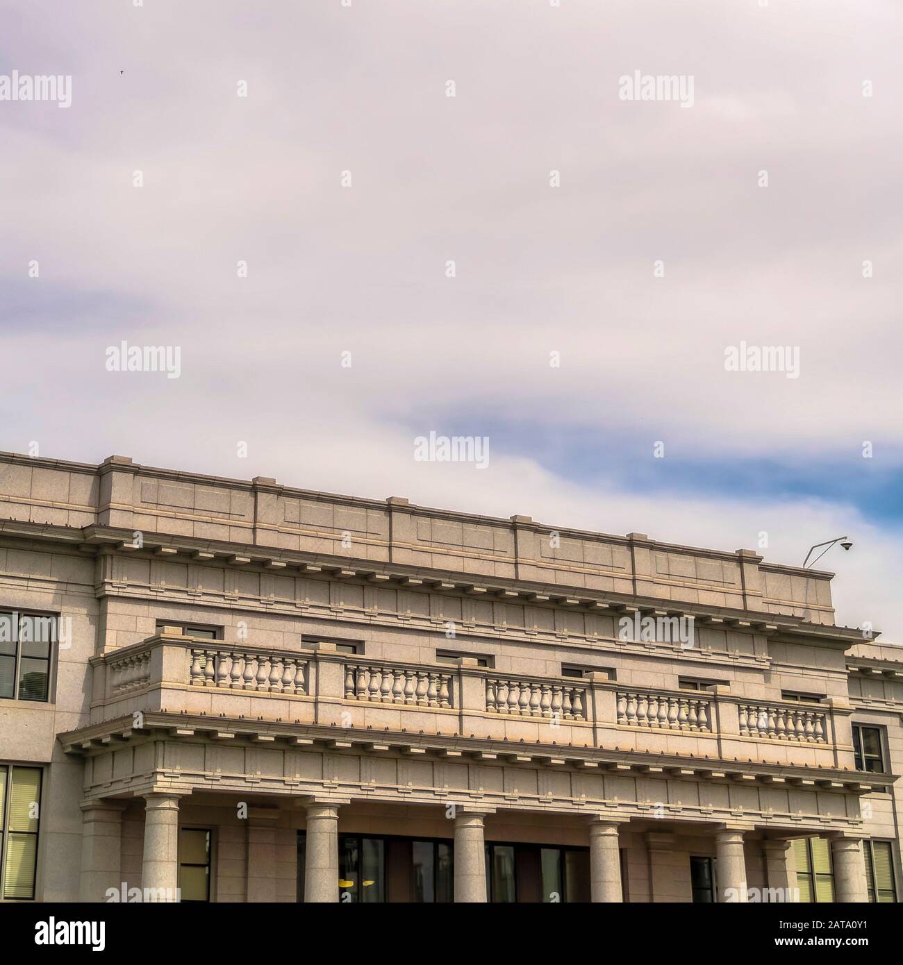 Cornice quadrata cielo blu nuvoloso sopra l'edificio con balcone e colonne enormi all'entrata Foto Stock
