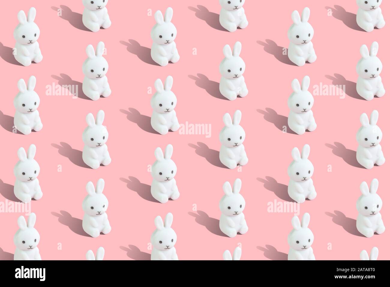 Modello Pasqua senza cuciture composto da coniglietti bianchi su sfondo rosa pastello concetto creativo minimo. Foto Stock