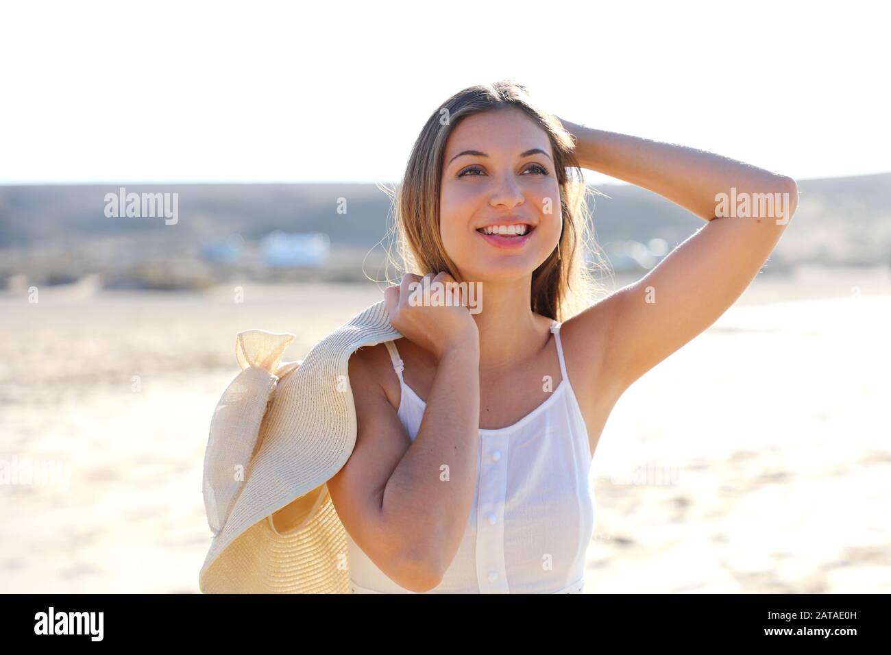 Attraente giovane donna divertirsi sulla spiaggia tenendo un grande  cappello di paglia Foto stock - Alamy
