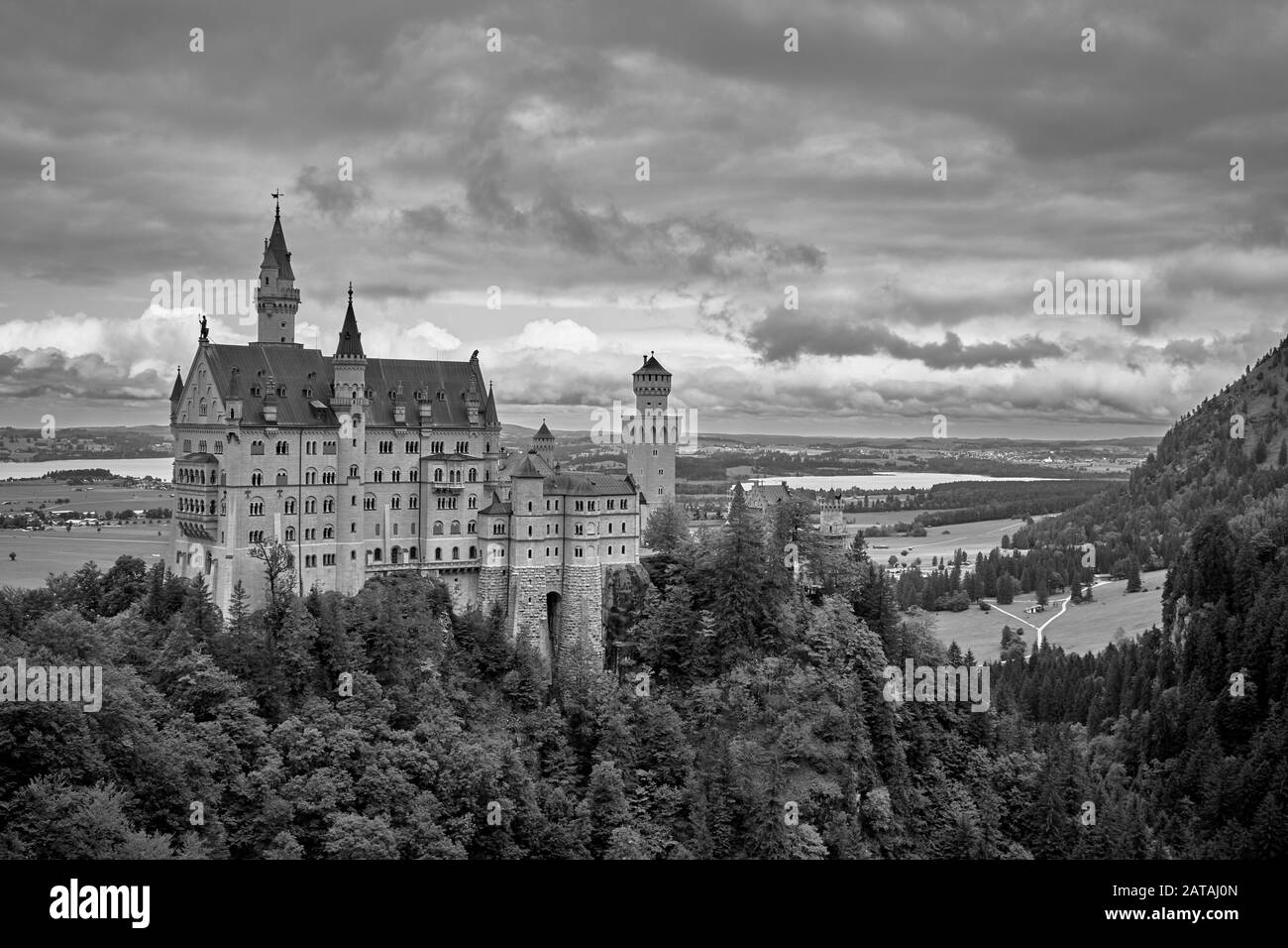 Castello di Neuschwanstein circondato dalla splendida natura delle Alpi Bavaresi e da un cielo drammatico in bianco e nero Foto Stock