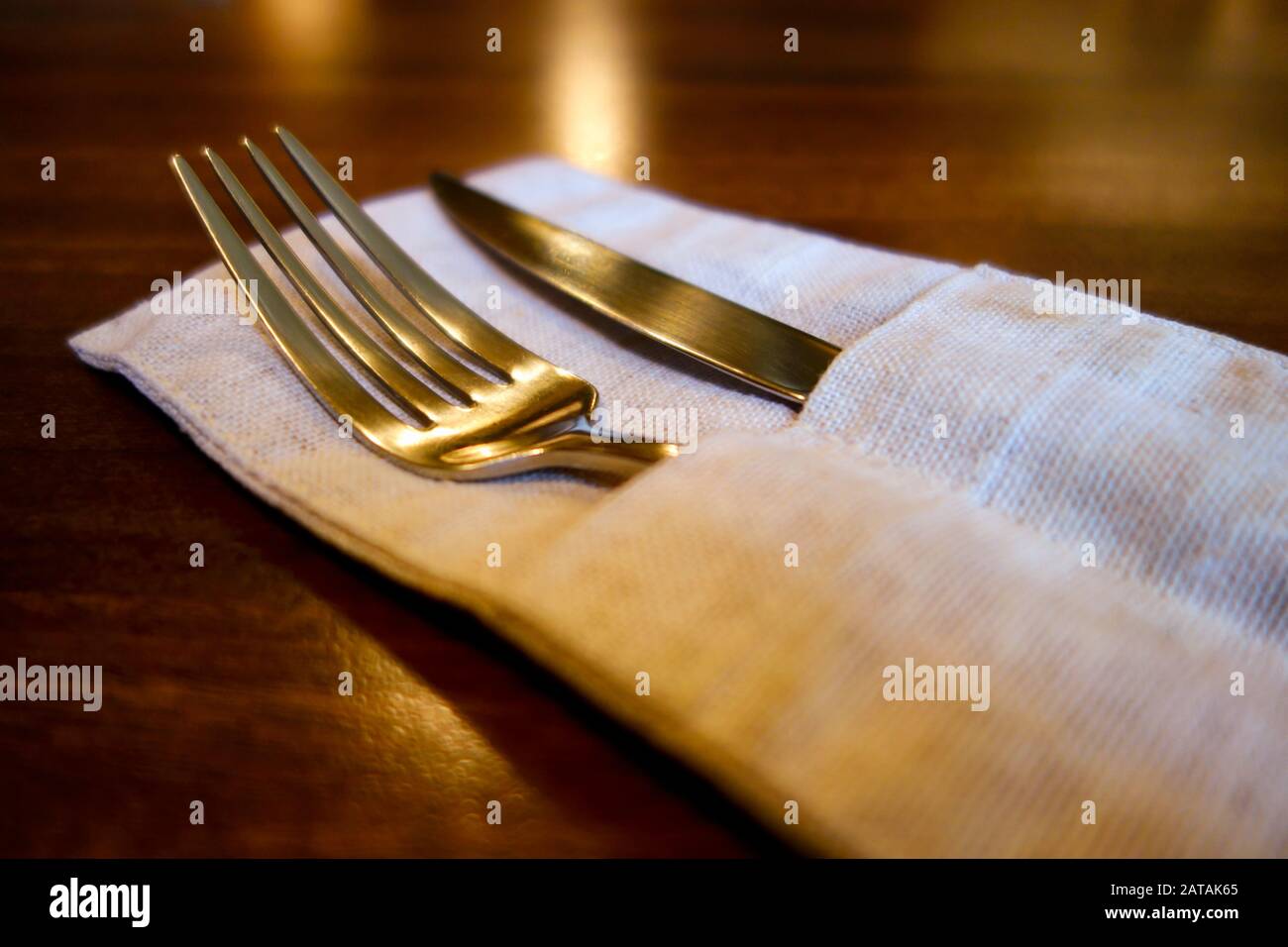 Coltello da tavolo e forchetta in tasche di lino sul tavolo di legno. Primo piano. Foto Stock