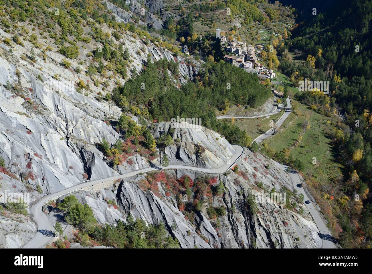 VISTA AEREA. Solo strada di accesso, attraverso un paesaggio geologicamente interessante per un villaggio remoto. Puget-Rostang, il backcountry della Costa Azzurra, Francia. Foto Stock