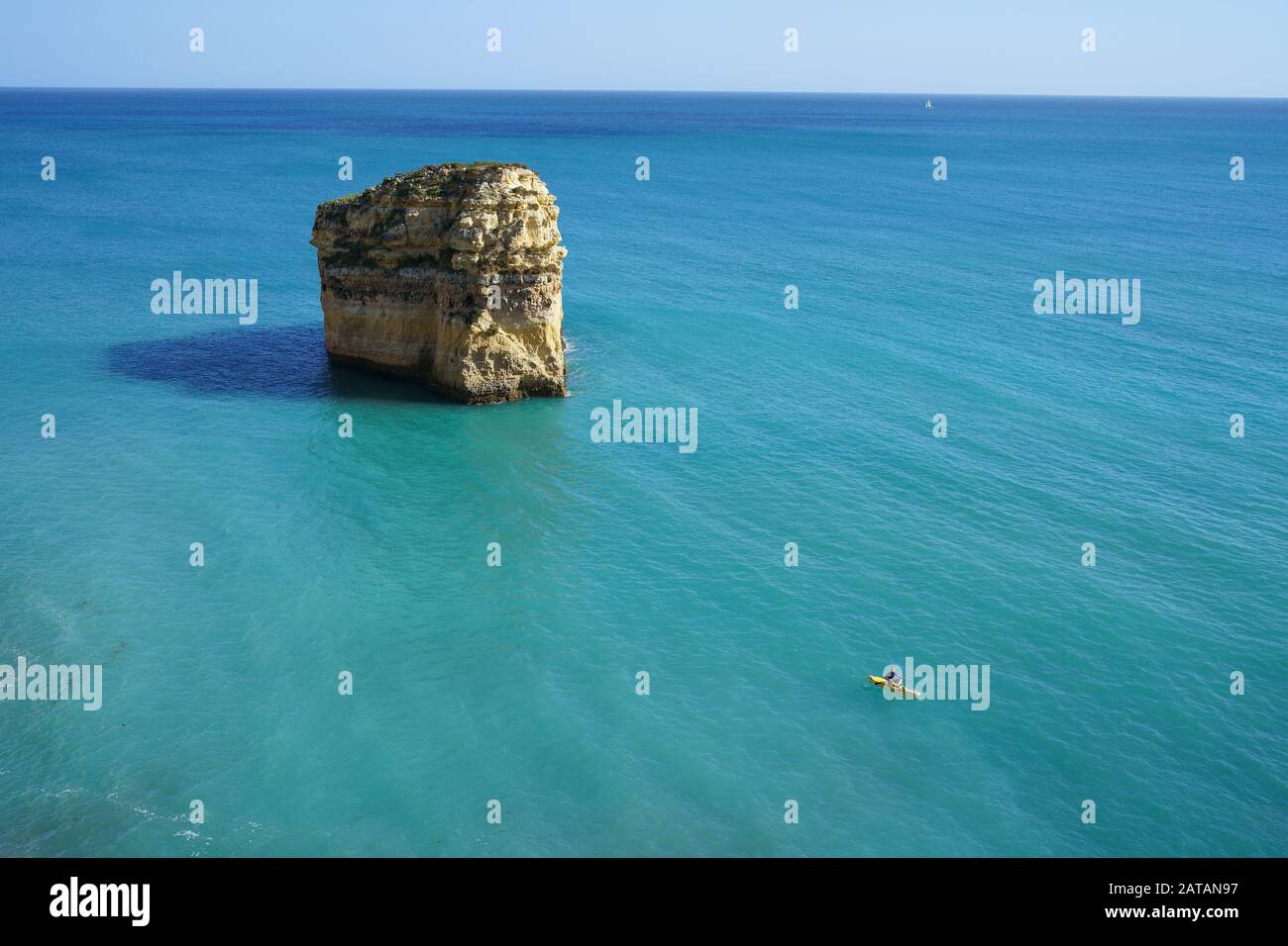 Vista in alto di un giovane uomo su un pedalò vicino a un maestoso catasta di mare. Praia do Barranquinho, Lagoa, Algarve, Portogallo. Foto Stock