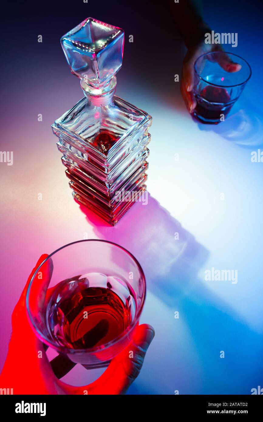 Caraffa quadrata in vetro con liquore e due bicchieri di vetro. Due persone bevono alcolici vista dall'alto Foto Stock