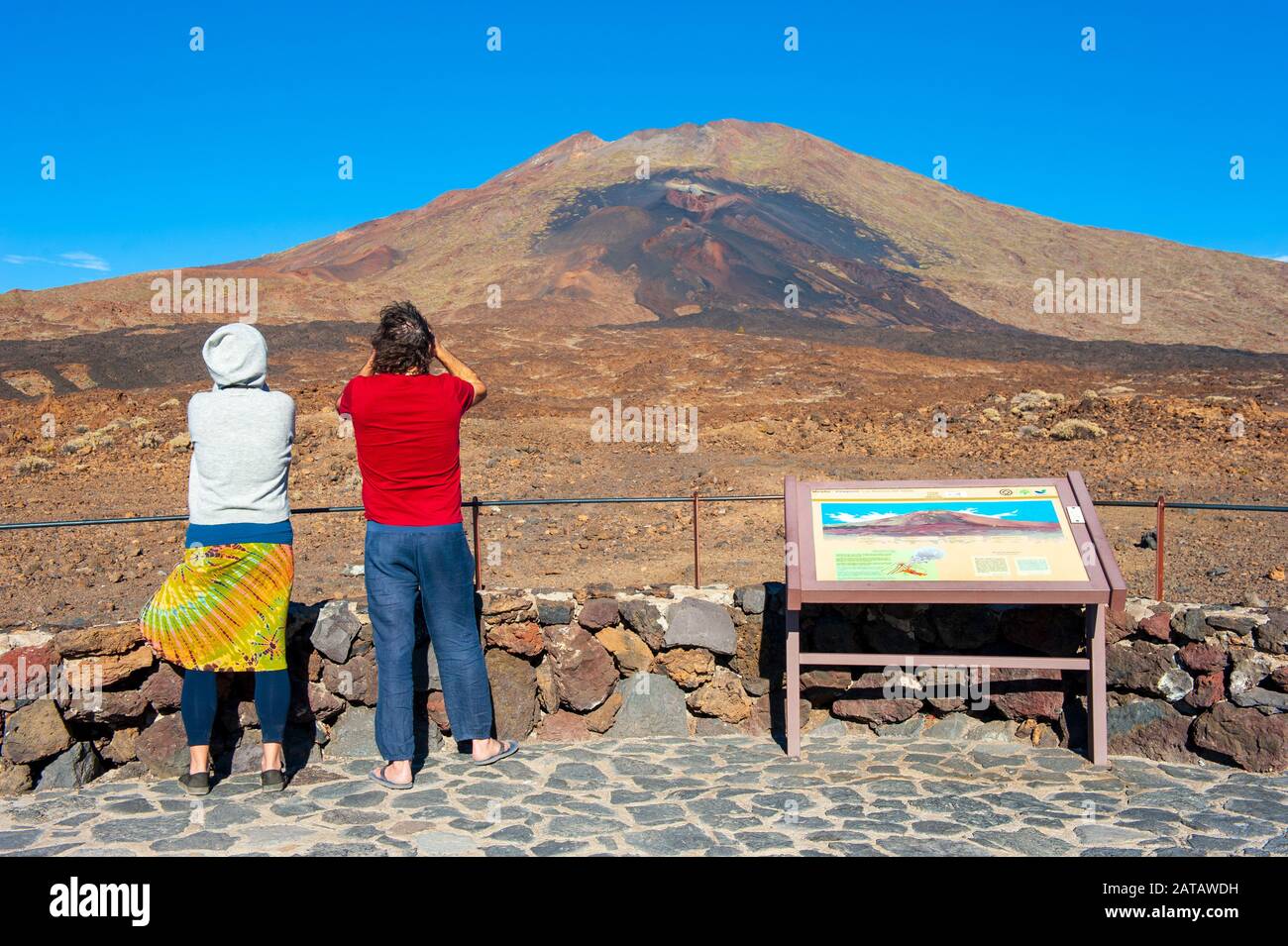 Canary ISLAND TENERIFE, SPAGNA - 24 dicembre 2019: Turisti con binocolo che guardano la lava viola e marrone dalle bocche inferiori del vulcano Pico vie Foto Stock