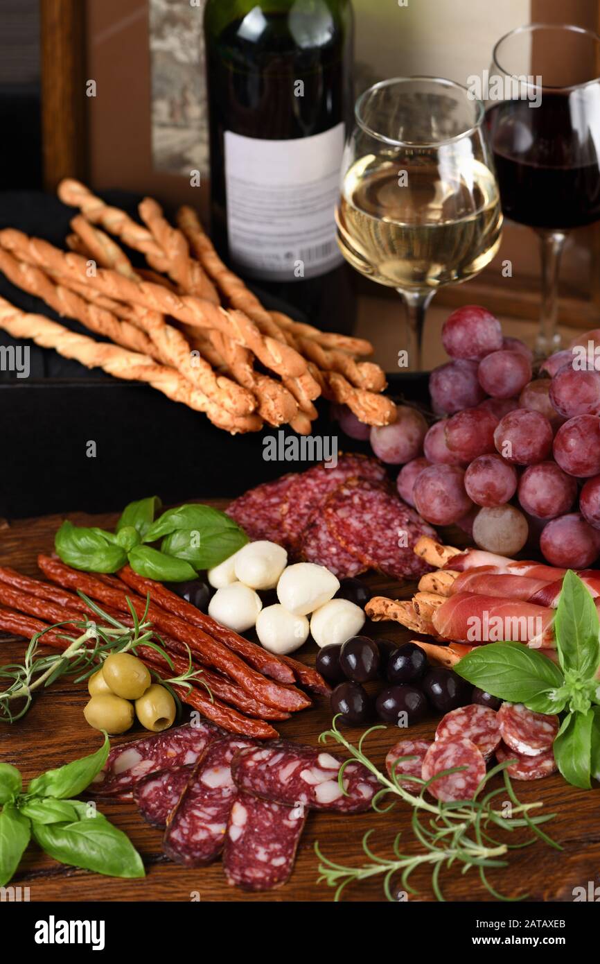 Antipasto. Piatto con salsicce, prosciutto, salame, croccanti grissini con uve. Un antipasto a base di carne è una grande idea per il vino. Foto Stock