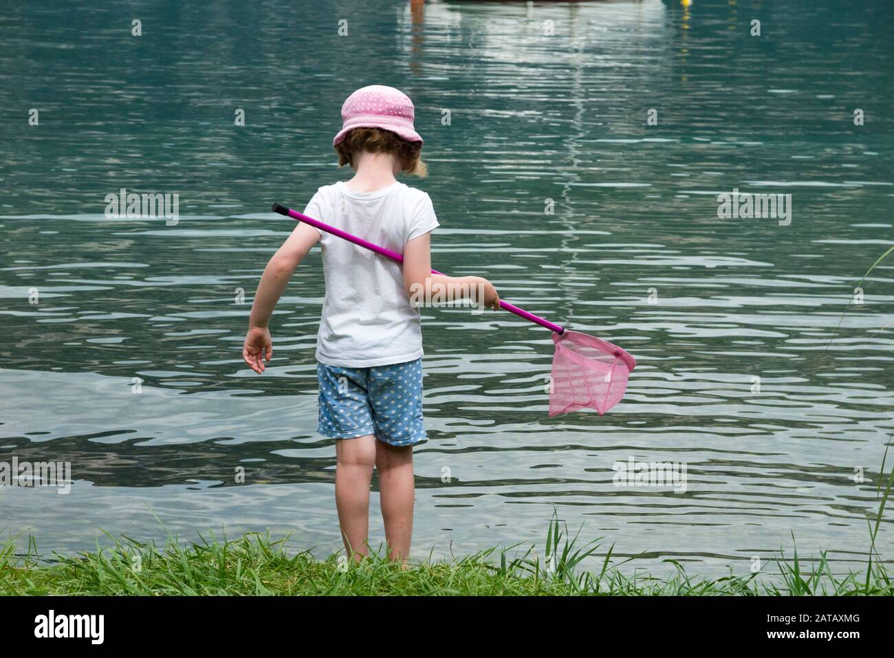 Ragazza / capretto con protezione del cappello del sole, cappelli & rete di  pesca / capretti / caccia del bambino per il pesce a Conjux, sopra /  accanto al lago du Bourget (
