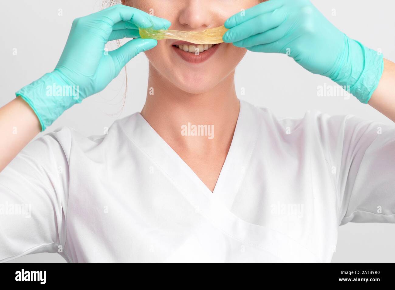 Estetista che tiene pasta liquida di zucchero come baffi, primo piano. Foto Stock