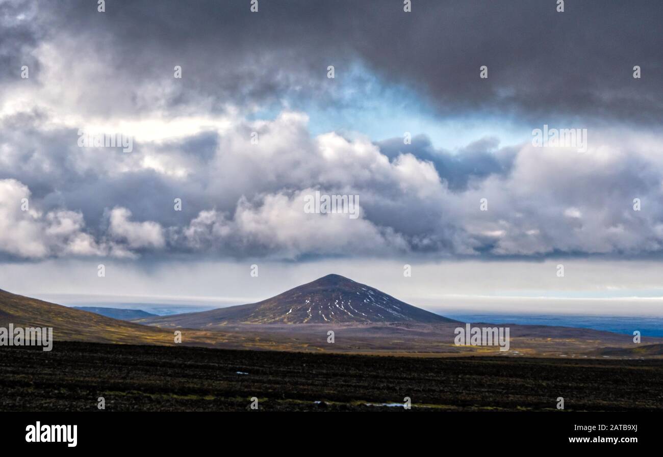 Ein Vulkan nel weiter Ferne im Herzen Islands. Solche Wolkenkompositionen sind auf dieser Insel keine Seltenheit. Foto Stock