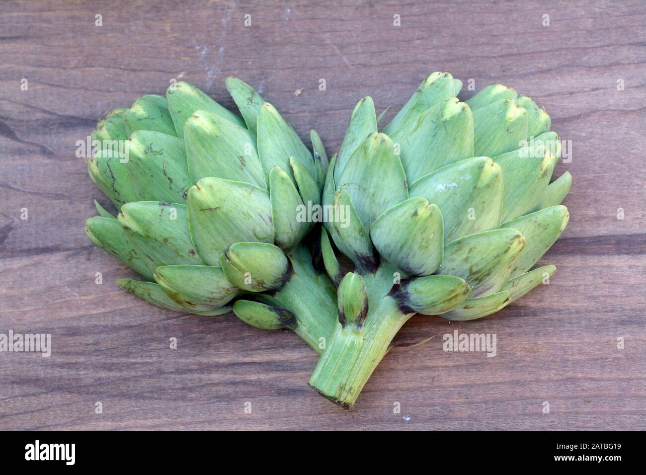 Due carciofi su tavola di legno Foto Stock