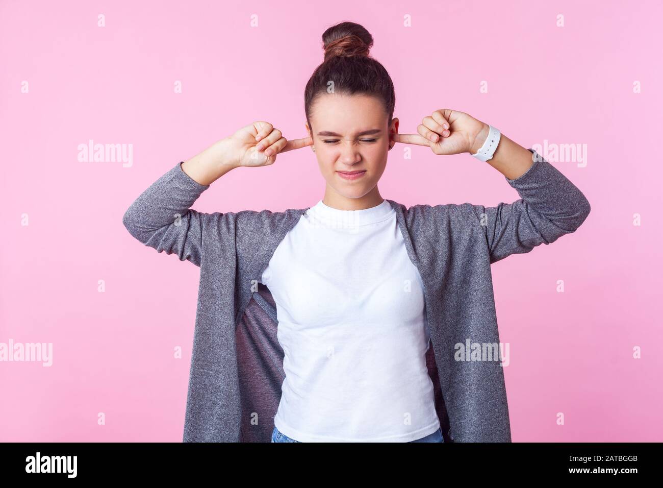 Non vuoi ascoltare! Ritratto di ragazza bruna naughty con capelli di bun in vestiti casuali che coprono le orecchie ignorando upbring parentale, t disobbediente Foto Stock