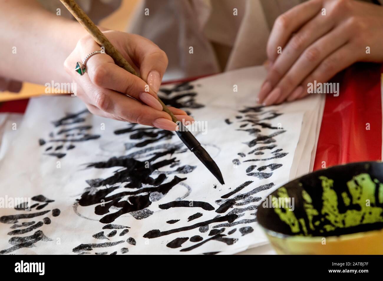 Closeup vista della mano con pennello di giovane donna che imparare a scrivere i caratteri cinesi durante la lezione di Calligraphy in una scuola Foto Stock