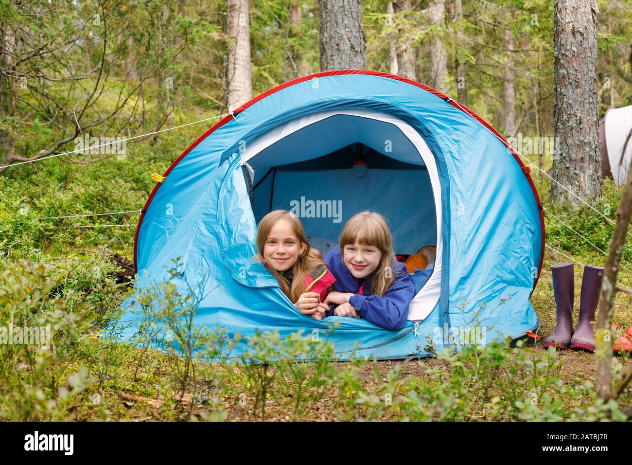 Tween ragazze che si trovano insieme in tenda godendo campeggio in una foresta estiva durante le vacanze estive Foto Stock