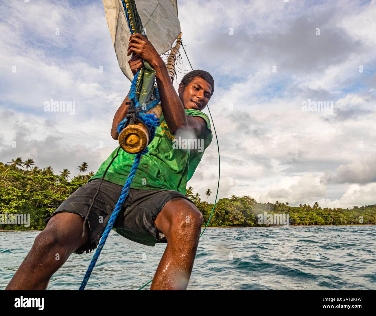 Navigazione in stile polinesiano su una barca a vela Proa (multiscafo a vela) nelle Isole Deboyne, Papua Nuova Guinea. Il terzo membro dell'equipaggio di un prau si occupa della parte superiore della vela. Poiché l'imbarcazione è simmetrica longitudinalmente, la poppa e la prua vengono scambiate quando si cambia direzione. Nella foto la punta della vela viene trasferita Foto Stock