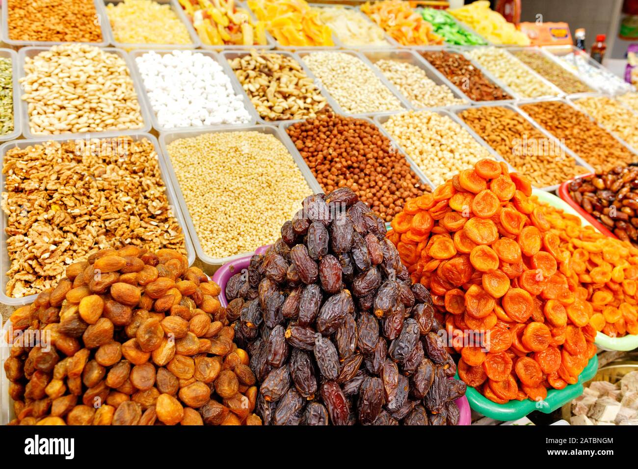 I vetrini con datteri, albicocche secche, mandorle, nocciole, noci, castagne in sfocatura sono venduti sugli scaffali del mercato orientale. Foto Stock
