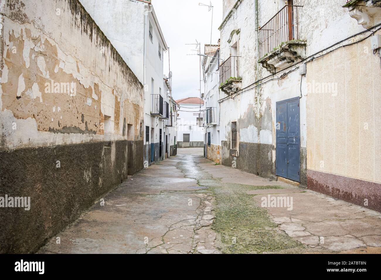 Via di una città nella Spagna occidentale con costruzioni molto vecchie di alloggio e una strada in cattive condizioni di manutenzione Foto Stock