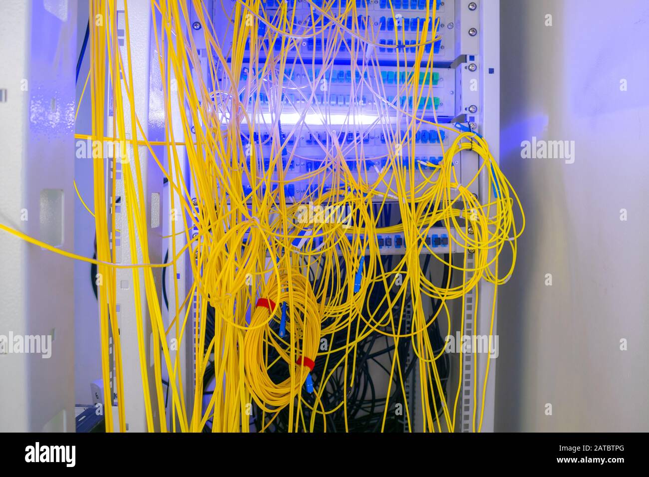 I fili batch sono collegati Nel Telaio Di distribuzione della fibra Ottica. I cavi disordinati sono intrecciati nel rack della sala server. I fili in fibra ottica sono posizionati Foto Stock