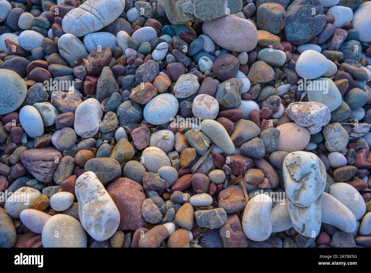 Splendido sfondo di rocce rotonde e colorate. Una scena tranquilla da una spiaggia incontaminata sull'oceano. Pietre sferiche e ondulate sulla riva del mare Foto Stock