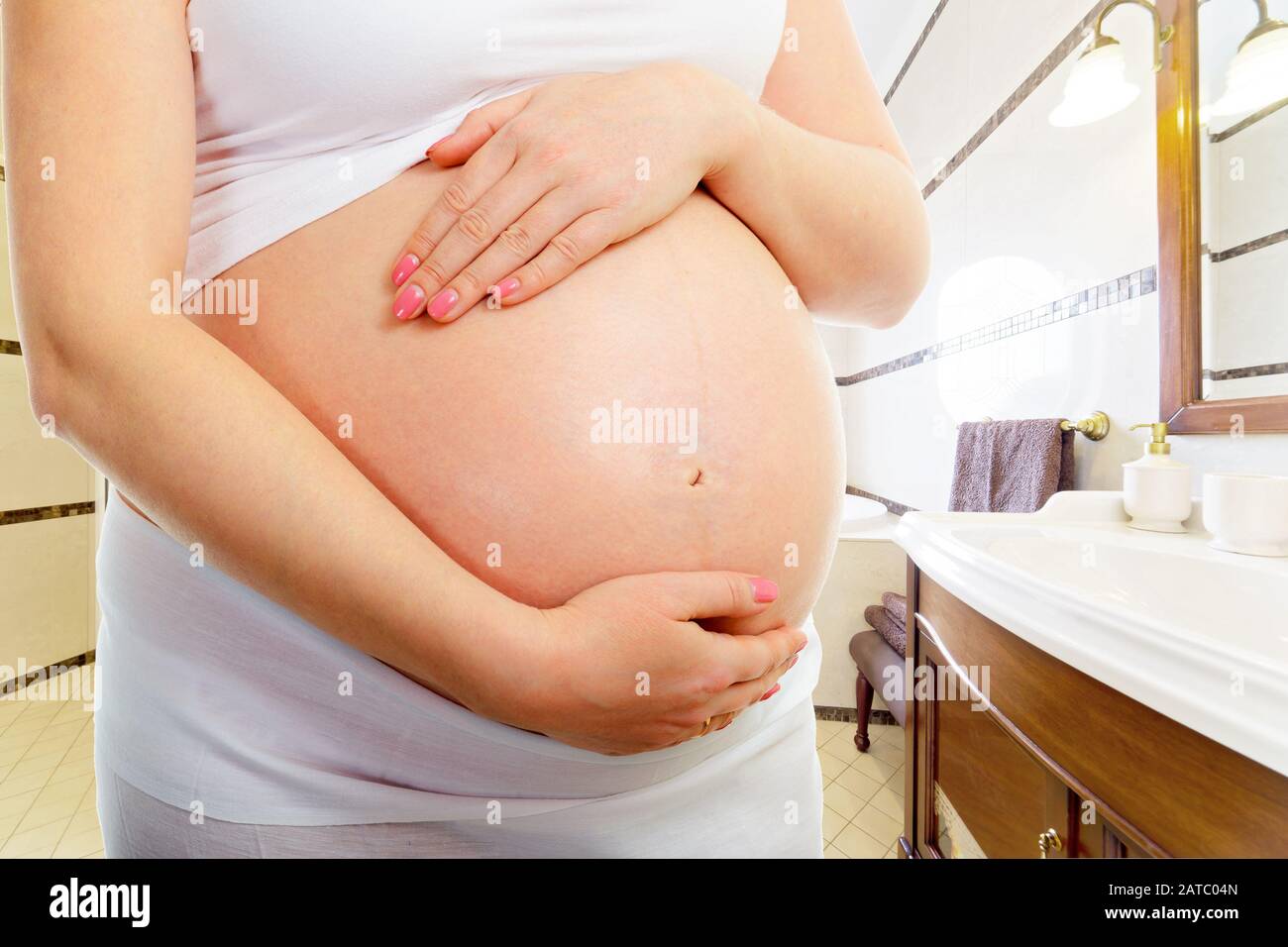 Pancia di una donna incinta in bagno a casa Foto Stock