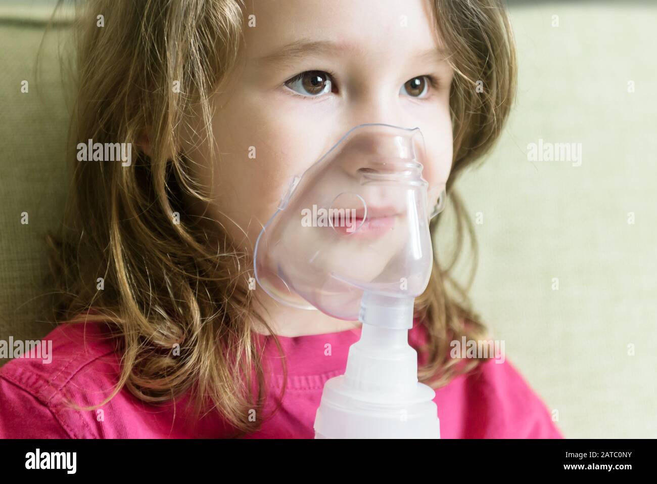 Bambina con maschera inalatore da vicino. Bambino malato respira attraverso un nebulizzatore a casa. Faccia del toddler che usa l'apparecchiatura per trattare l'asma o la bronchite. Foto Stock