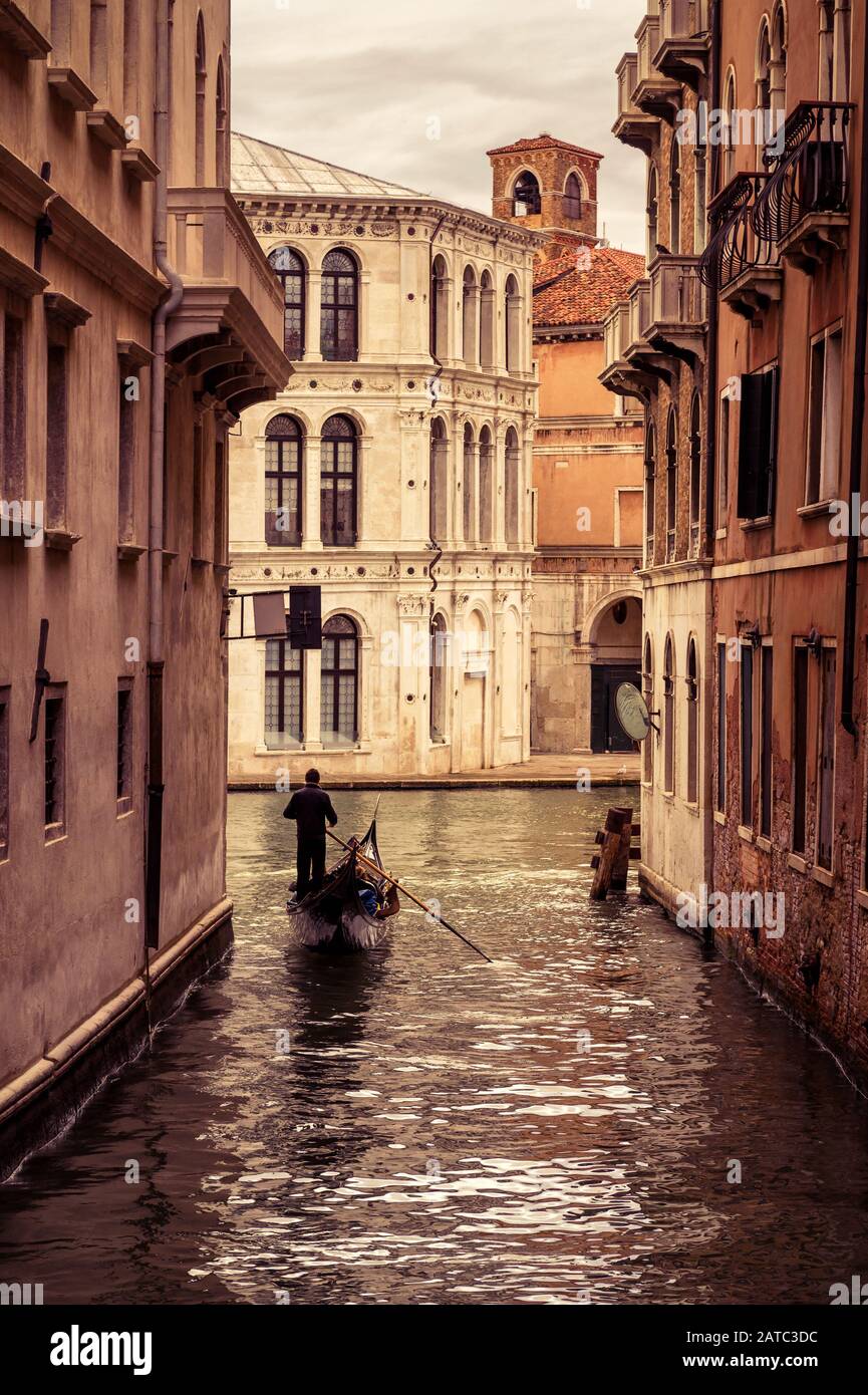 Gondola con turisti galleggia lungo lo stretto canale di Venezia, Italia. La gondola è il mezzo di trasporto turistico più attraente di Venezia. Foto Stock