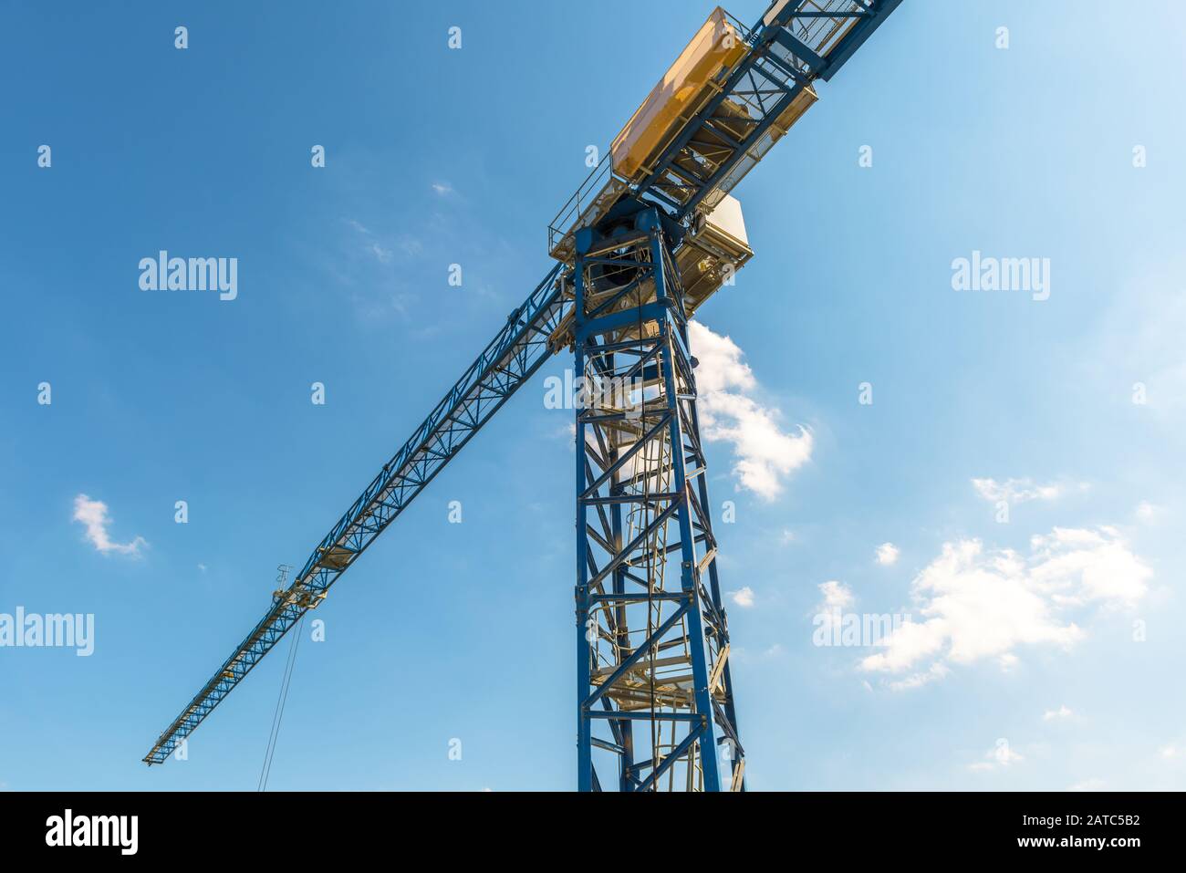 Gru da cantiere sullo sfondo blu del cielo. Vista ad angolo basso del braccio e della torre della gru. Panorama di macchinari pesanti nella soleggiata giornata estiva. Lo Foto Stock