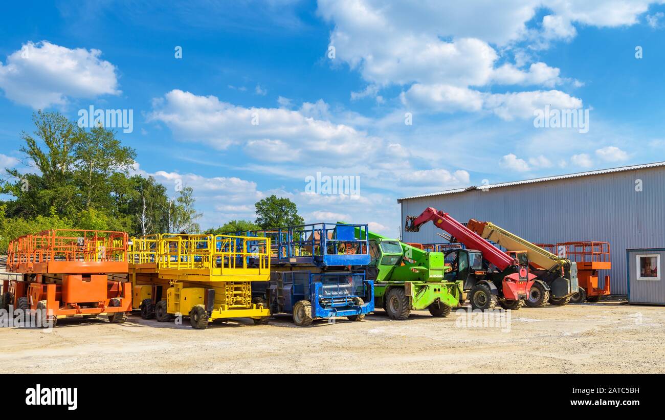 Macchine da costruzione in estate. Veicoli colorati e camion pesanti nel parcheggio all'aperto. Panorama delle attrezzature di riparazione in giornata di sole. Foto ciliegia Foto Stock