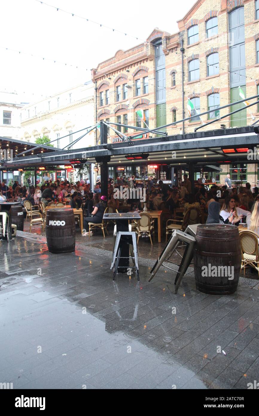 La piazza del concerto a Liverpool, in tempo piovoso, in estate. Molti ospiti si siedono all'esterno. Cavern Quarter, Liverpool. Inghilterra, Europa. Foto Stock
