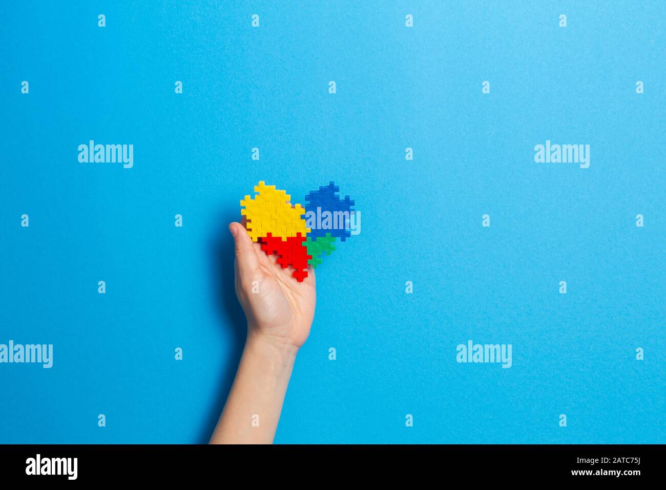 Bambino mano azienda cuore colorati su sfondo blu. Mondo autismo consapevolezza giorno di concetto Foto Stock