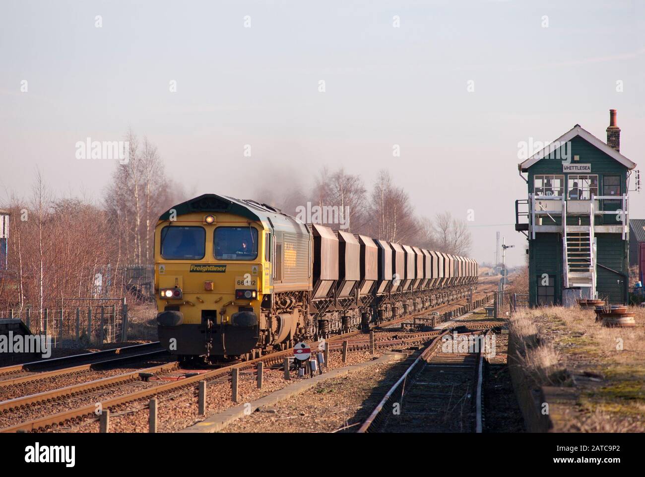 Una locomotiva diesel classe 66 Freightliner numero 66602 che passa attraverso la scatola segnale Whittlesea con un treno di carri tramoggia per pietra. Foto Stock