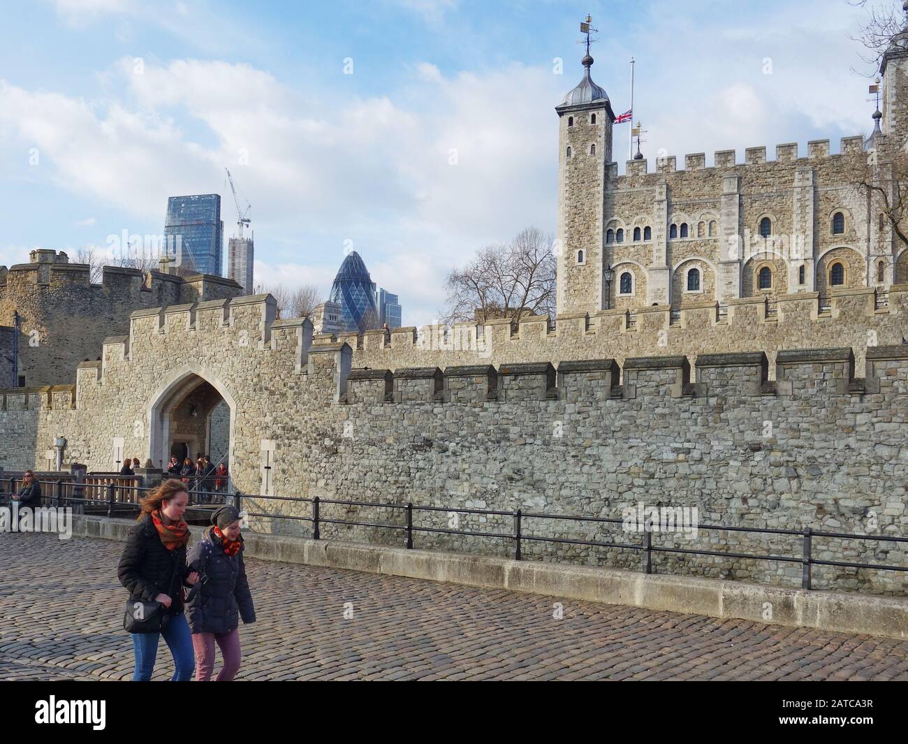 2 giovani passeggiano davanti alla Torre di Londra con il quartiere finanziario della città sullo skyline Foto Stock