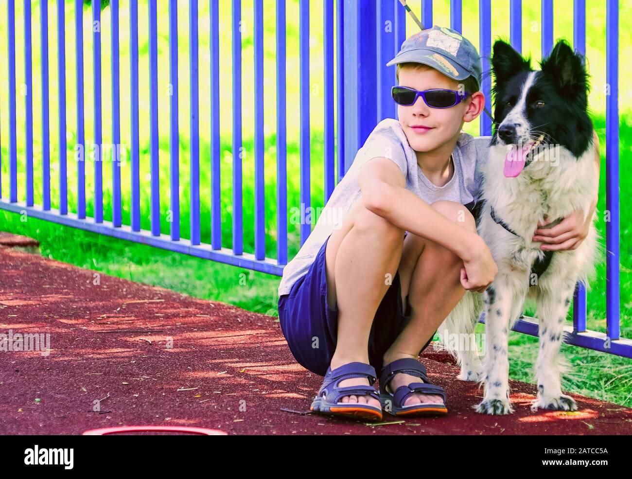 Un ragazzo in vetri scuri sta squattando accanto ad un cane . Foto Stock