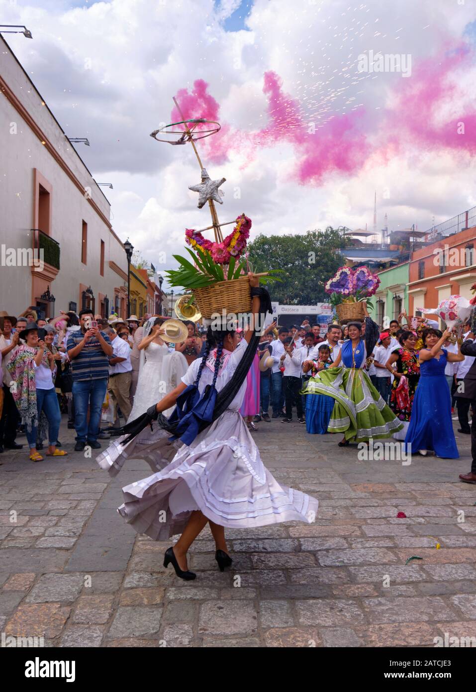 Donna che gira in un abito tradizionale scorrevole con cesto di fiori illuminato Parte della tradizionale sfilata di nozze (Calenda de Bodas) per le strade di Oaxaca. Foto Stock