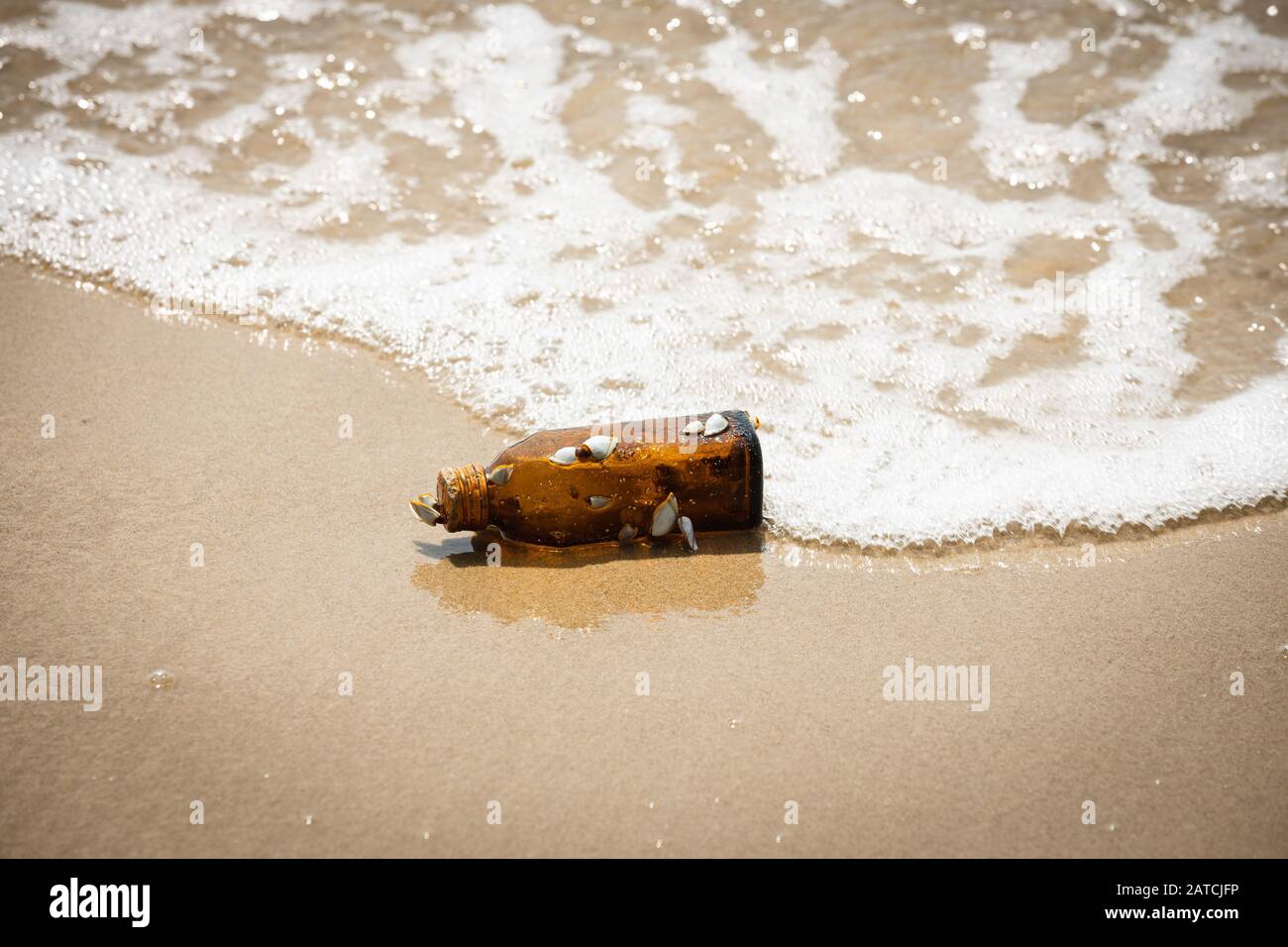 Bottiglia in vetro ambrato con coperchio arancione da fissare per gruppo di pinnacoli. Pezzo di spazzatura sulla spiaggia. Foto Stock