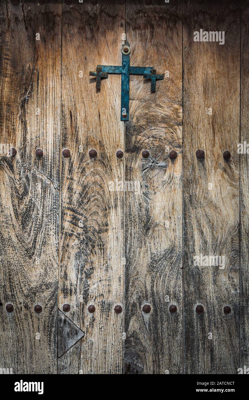 Porta in legno antica decorata con una croce in ghisa e borchie in ferro Foto Stock