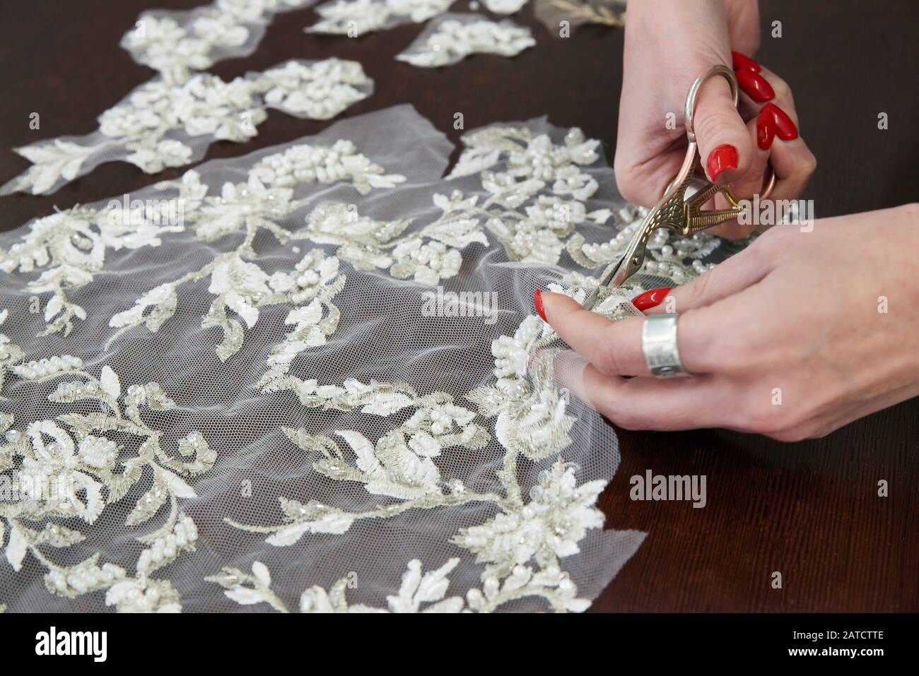 fuoco selettivo di seamstress seduta al tavolo, macchina da cucire e taglio pizzo con forbici in studio di cucito Foto Stock